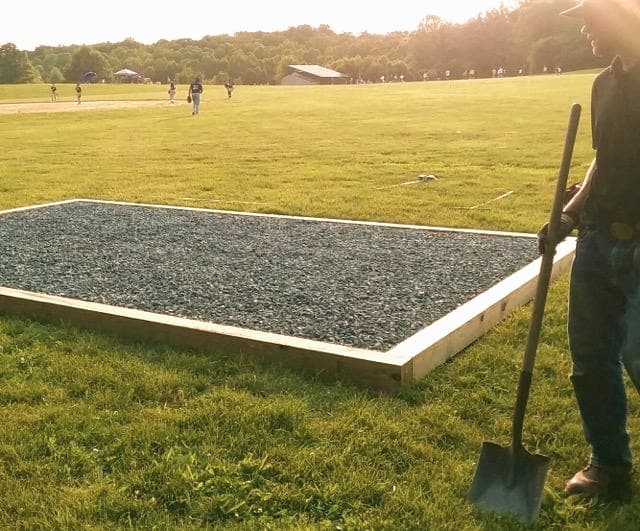 Completed gravel pad foundation in a clean fenced backyard