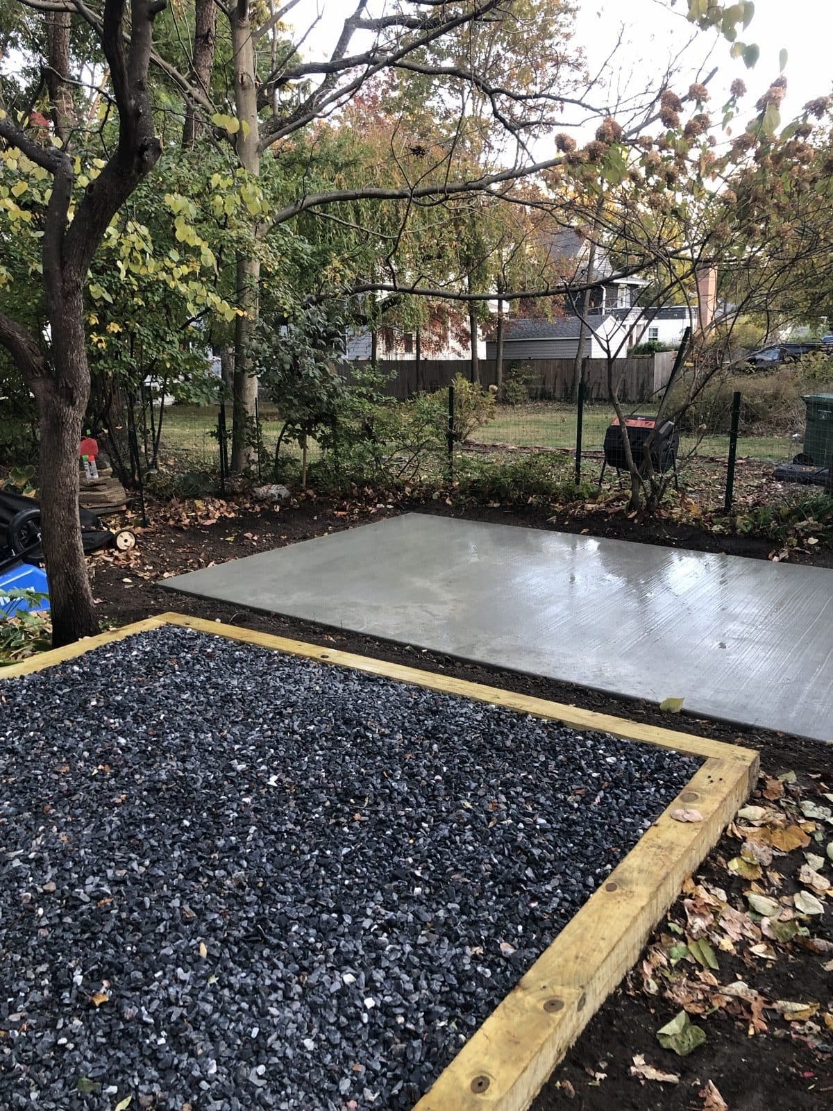 A framed gravel pad and a finished concrete slab built side by side in the same backyard