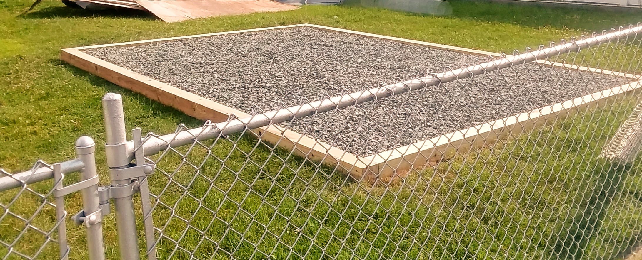 Gravel pad installed alongside a chain-link fence in a narrow yard