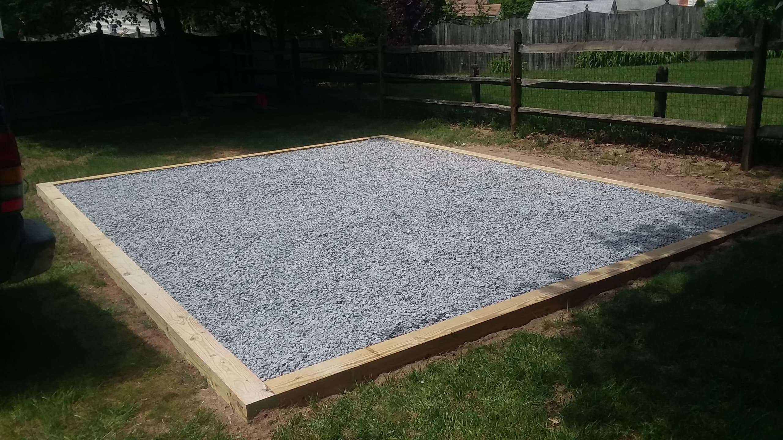 Standard square gravel pad next to a wooden fence
